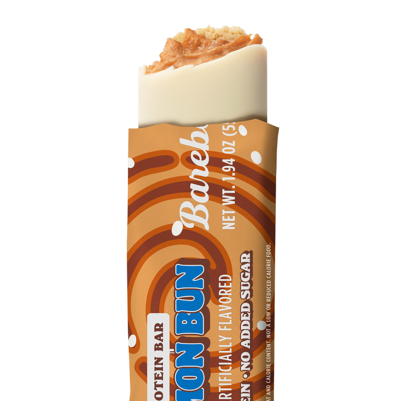 Barebells Cinnamon Bun protein bar unwrapped, showing white chocolate coating with cinnamon bun-flavored crispy topping