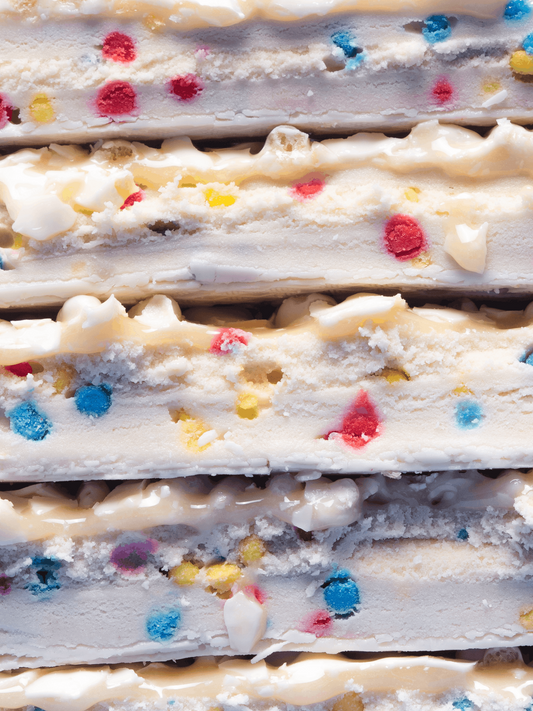 Barebells Birthday Cake bar cross-section showing vanilla cake layers with white frosting and colorful sprinkles