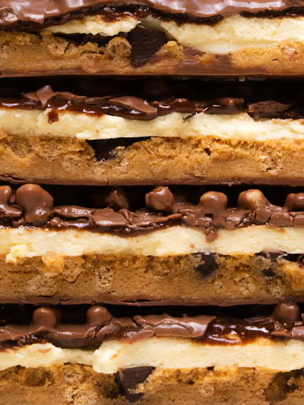 Barebells Camp S'mores protein bar cross-section showing layers of graham cracker, marshmallow, chocolate, and caramel filling