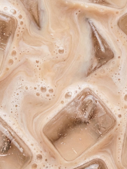Barebells Cookie Milk drink with ice cubes and bubbles in creamy beige liquid