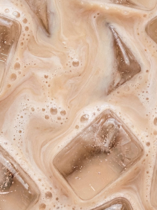 Barebells Cookie Milk drink with ice cubes and bubbles in creamy beige liquid