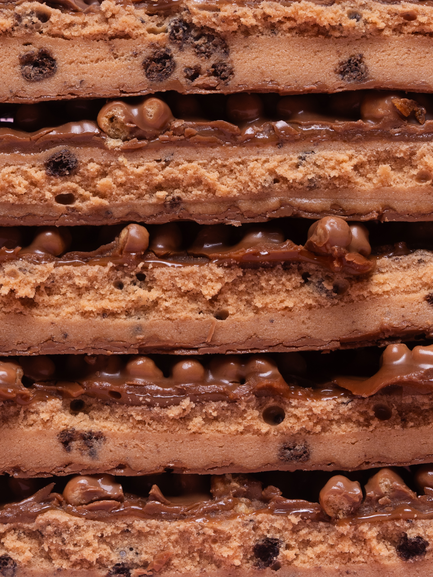 Barebells Cookies Caramel bar cross-section showing cookie layers with caramel filling and chocolate pieces