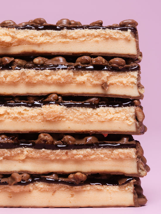 Stack of five Barebells Creamy Crisp protein bars showing layered structure with crispy coating, creamy center and chocolate pieces