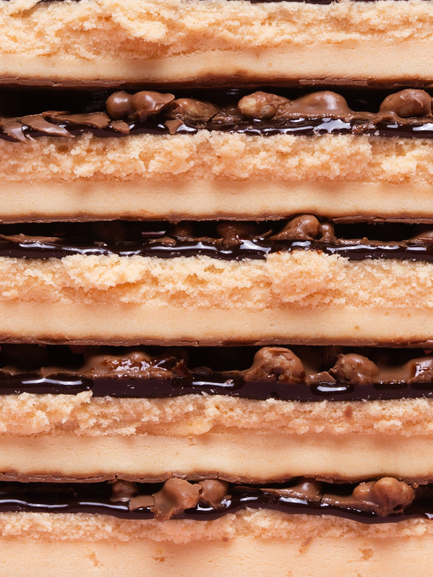 Barebells Creamy Crisp bar cross-section showing layers of crispy coating, creamy filling, and chocolate with peanuts
