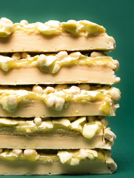 Stack of five Barebells Key Lime Pie protein bars with lime filling and white chocolate pieces on green background