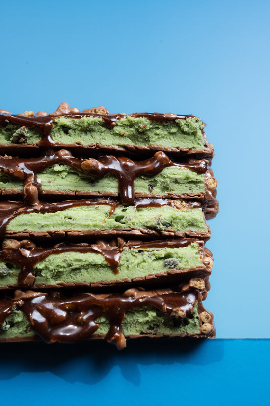 Stack of five Barebells Mint Chocolate Crisp bars cut in half, showing mint green layers with chocolate coating and crispy pieces between each bar