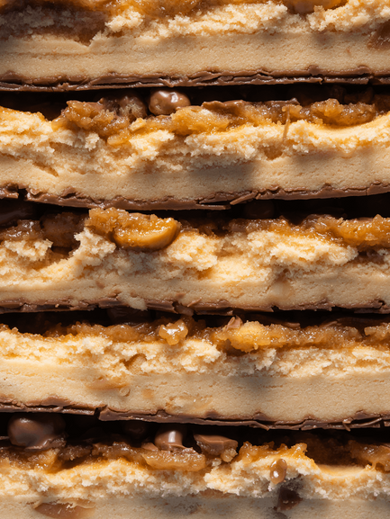 Barebells Peanut Butter protein bars stacked showing layers of peanut butter filling, chocolate coating and crunchy peanut pieces
