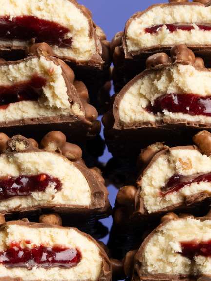 Barebells Peanut Butter Jelly bars cut in half revealing cream filling with red jelly center and peanut pieces