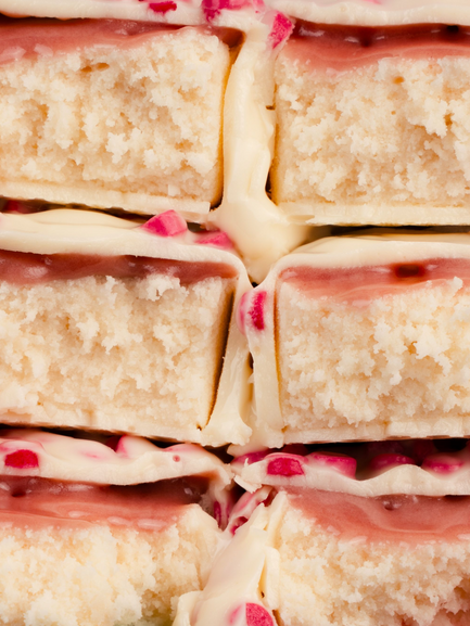 Barebells Peppermint Bark protein bars stacked showing white chocolate coating with pink peppermint pieces and textured cake interior