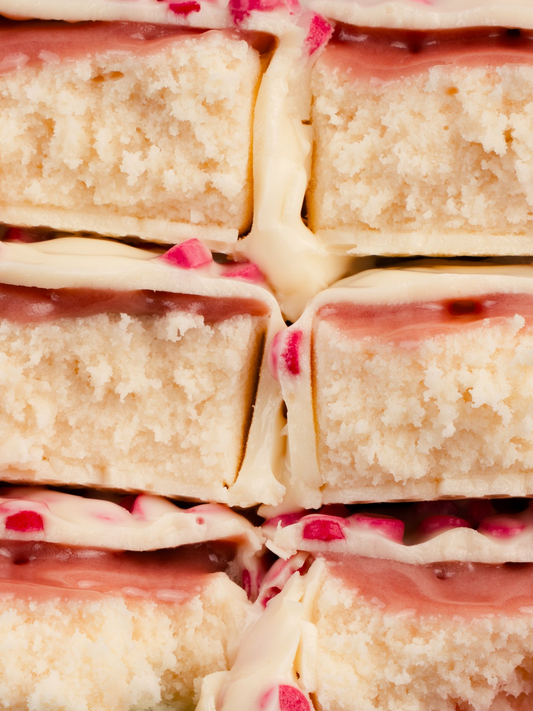 Barebells Peppermint Bark protein bars stacked showing white chocolate coating with pink peppermint pieces and textured cake interior