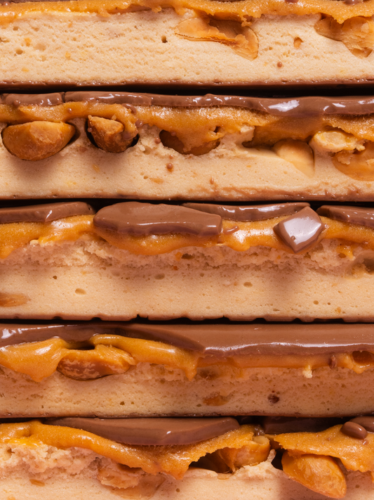 Barebells Salted Peanut Caramel protein bars stacked showing layers of peanut pieces, caramel, chocolate coating and peanut butter filling